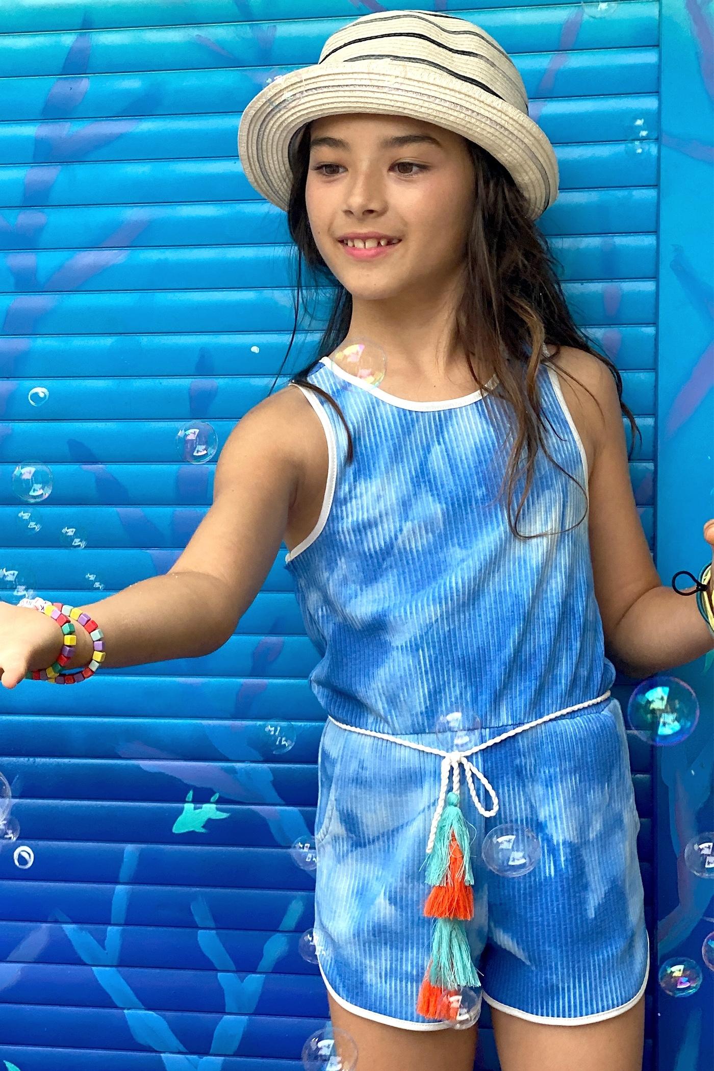 My hannah banana Girl’s Tie Dye Ribbed Knit Tassel Belt Romper.   Round Neckline & Sleeveless Ribbed Knit Material  Contrast Solid Trim Outline  Cloud or Water Tie Dye   A Minimal Boho Tassel Belt Semi Curved Sporty Short  Spring & Summer Beach Vacation Ready   Imported