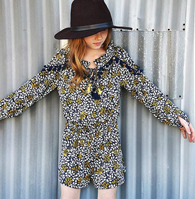 Big Girl Leaf Boho Pom Pom Tassel Romper  Round Ruffled Neckline  Pom Pom & Tassel Trim on Chest & Shoulders   Long Sleeves  Elastic Waistline  Perfect Tones for Transitional Fall/Winter   SELF: 94% Polyester / 6% Spandex, LINING: 100% Polyester  Easy and comfortable long sleeve knit romper. Comes in high quality knit printed with navy multicolor floral print. Lined for her comfort.  Embellished with navy pompom trim and colorful navy and yellow contrast tassel ties. 